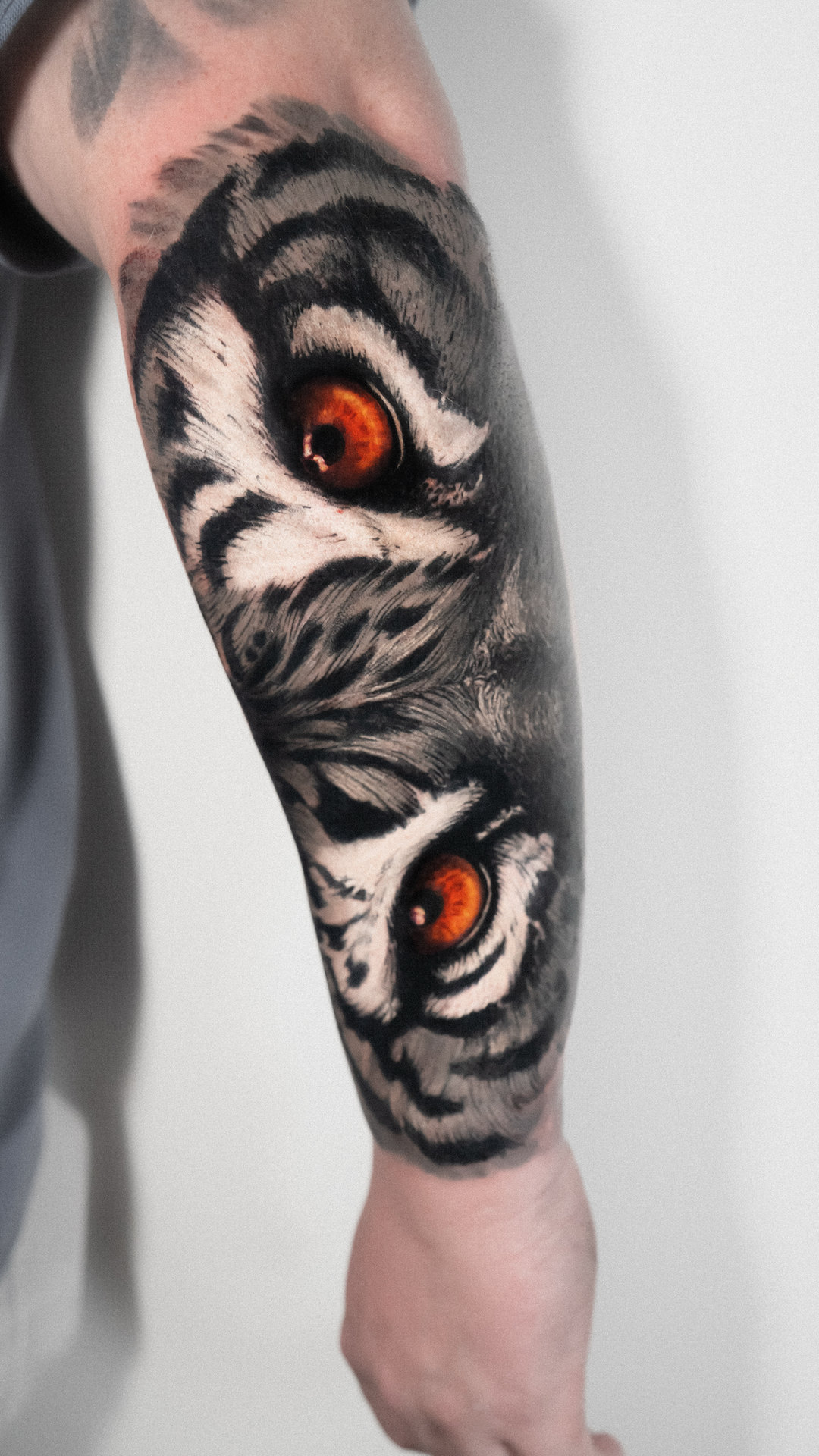 Black-and-gray tiger eyes forearm tattoo by Tony Vilella